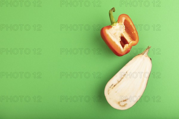 Red Cutted pepper and Purple Cutted eggplant on green pastel background. Top view, flat lay, copy space. Tropical, healthy food, vegetable, slice, minimalism