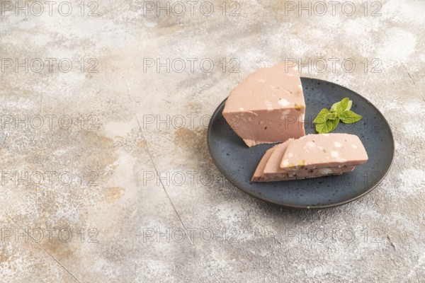 Mortadella sausage on wooden cutting board with pepper and herbs on brown concrete background. Side view, copy space