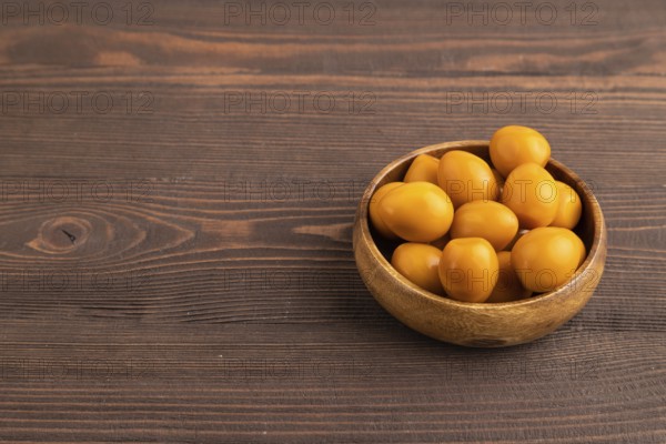 Pile of Smoked Quail eggs in bowl on a brown wooden background. side view, copy space
