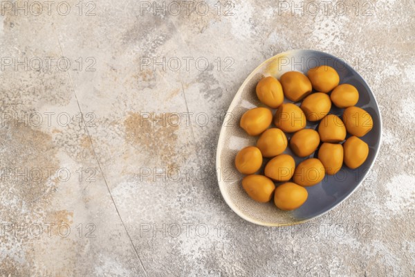 Pile of Smoked Quail eggs on plate on a brown concrete background. top view, flat lay, copy space