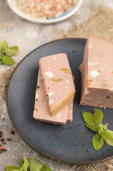 Mortadella sausage on plate with pepper and herbs on brown concrete background and linen textile. Side view, close up, selective focus