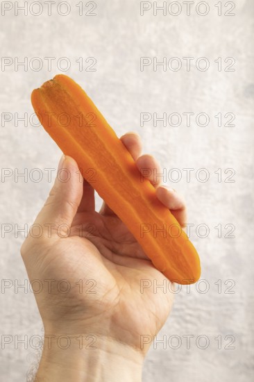 Orange Carrot with hand on gray concrete background. Top view, close up, flat lay. healthy food, vegetable, minimalism