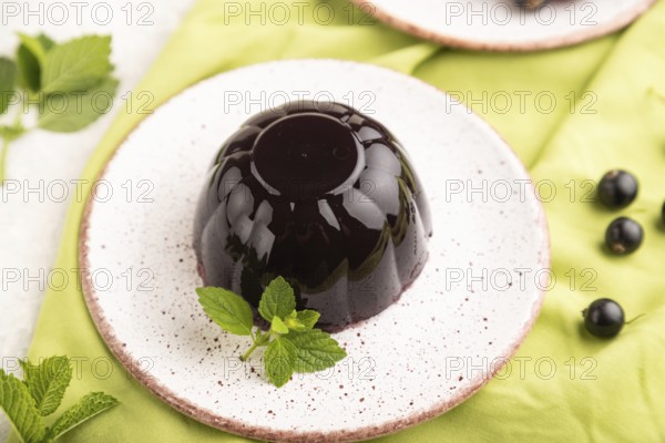 Black currant and grapes jelly on gray concrete background and green linen textile. side view, close up, selective focus