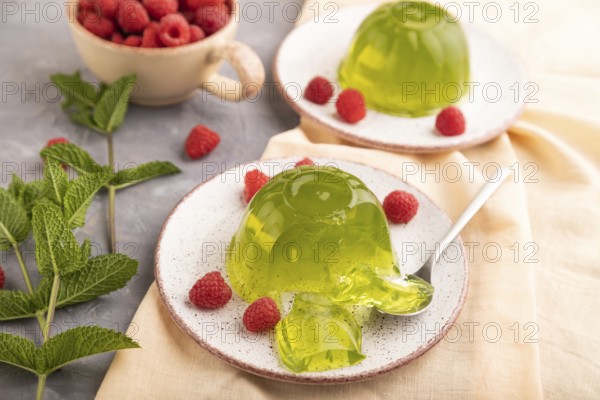 Mint and raspberry green jelly on gray concrete background and orange linen textile. side view, close up, selective focus
