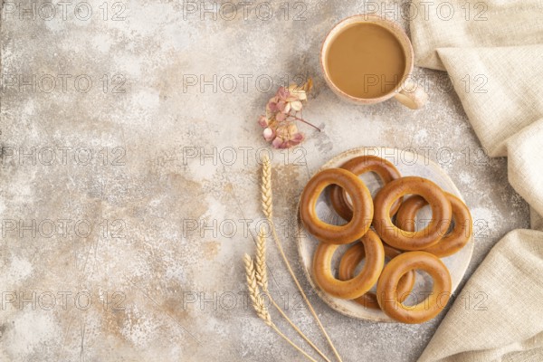 Homemade Ring Bagel with cup of coffee on brown concrete background and linen textile. top view, flat lay, copy space