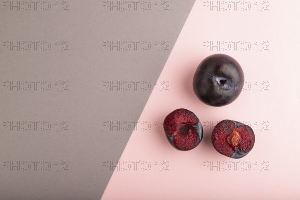 Purple Plum Cut in half on pink and gray pastel paper background. Top view, flat lay, copy space. healthy food, vegetable, minimalism