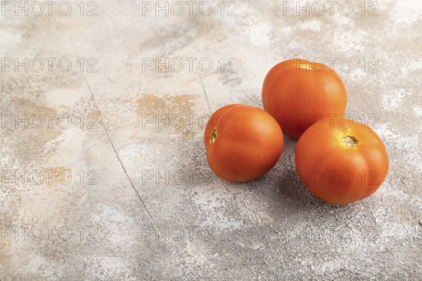 Red tomato on brown concrete background. Side view, copy space. healthy food, vegetable, minimalism