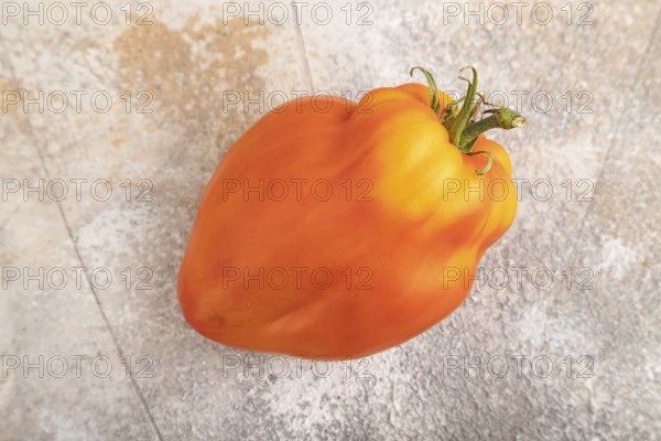 Red Heart Shape tomato on brown concrete background. Top view, flat lay, close up. healthy food, vegetable, minimalism
