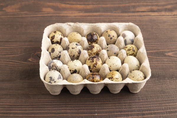 Pile of raw Quail eggs on brown wooden background. side view, flat lay, copy space