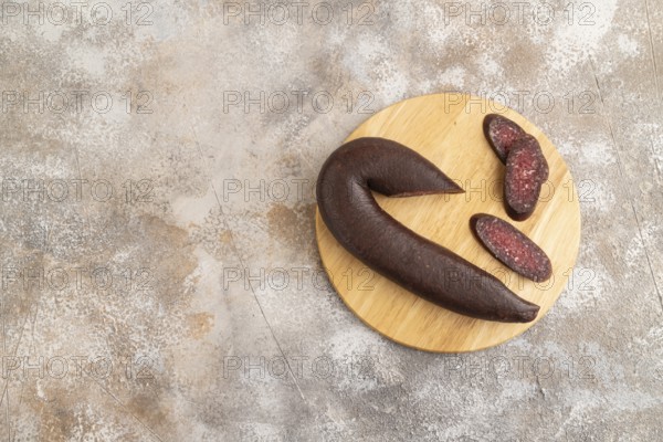 Sujuk sausage on wooden cutting board with pepper and herbs on brown concrete background. Top view, flat lay, copy space