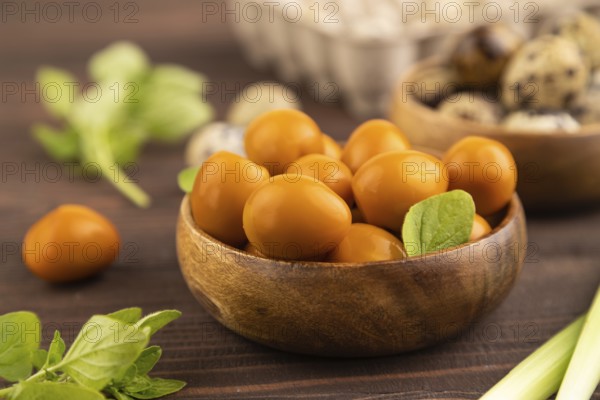 Pile of Smoked Quail eggs in bowl on a brown wooden background. side view, close up, selective focus