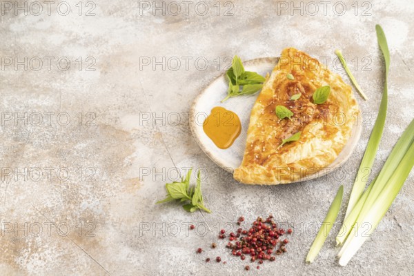 Fried homemade Khachapuri cake with cheese and meat, fried in pan. Traditional Georgian cuisine on brown concrete background. Side view, copy space