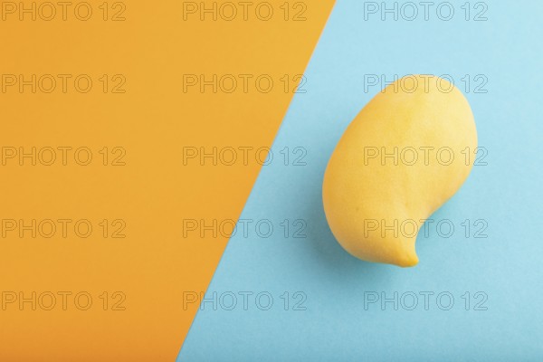 Orange mango on orange and blue paper pastel background. Side view, copy space. healthy food, minimalism