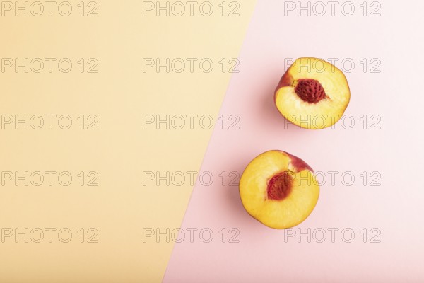 Peach Cut in half on orange and pink paper pastel background. Top view, flat lay, copy space. healthy food, minimalism