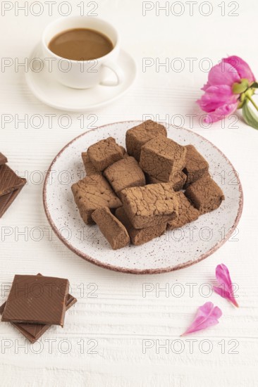Chocolate marshmallow with cup of coffee on white wooden background. side view, close up