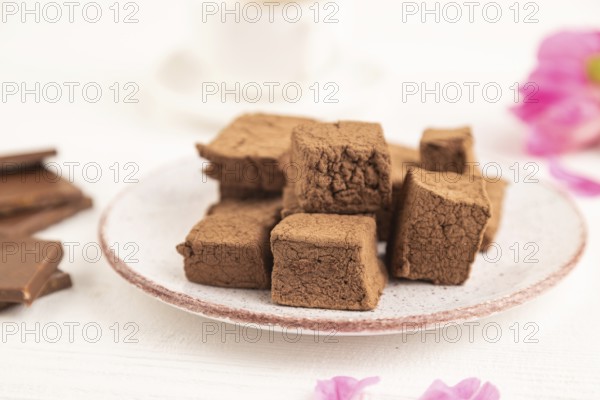 Chocolate marshmallow with cup of coffee on white wooden background. side view, close up, selective focus