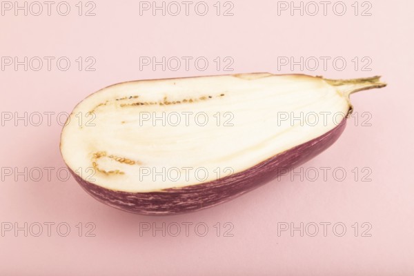 Purple Cutted eggplant with white stripes on pink pastel background. Side view, copy space. Tropical, healthy food, vegetable, slice, minimalism