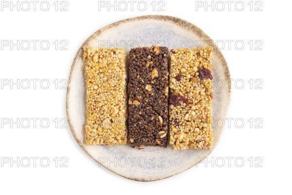 Granola bars with caramel, nuts, flakes in ceramic plate isolated on white background. Top view, flat lay, close up