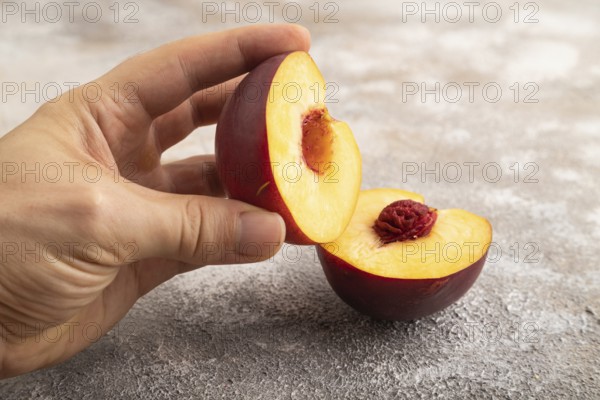 Peach Cut in half with hand on brown concrete background. Side view, copy space. healthy food, vegetable, minimalism