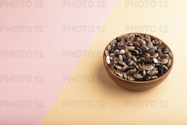 Wooden bowl with Kidney beans on pink and orange pastel paper background, side view, copy space, minimalism