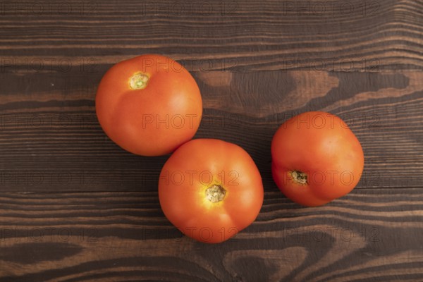 Red tomato on brown wooden background. Top view, flat lay, close up. healthy food, vegetable, minimalism
