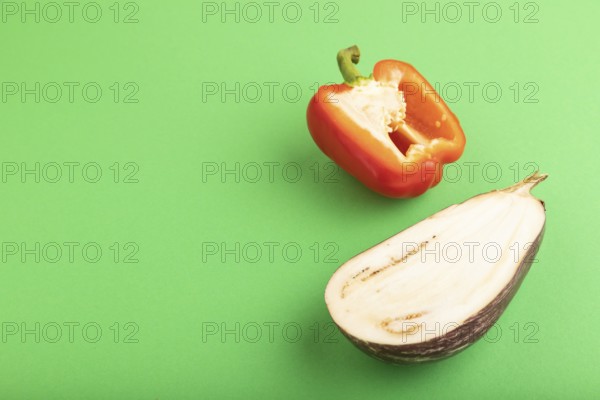 Red Cutted pepper and Purple Cutted eggplant on green pastel background. Side view, copy space. Tropical, healthy food, vegetable, slice, minimalism