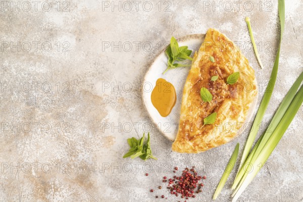 Fried homemade Khachapuri cake with cheese and meat, fried in pan. Traditional Georgian cuisine on brown concrete background. Top view, flat lay, copy space