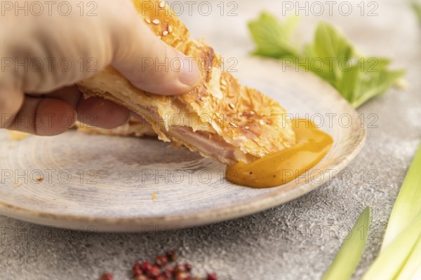 Fried homemade Khachapuri cake with hand with cheese and meat, fried in pan. Traditional Georgian cuisine on brown concrete background. Side view, close up, selective focus