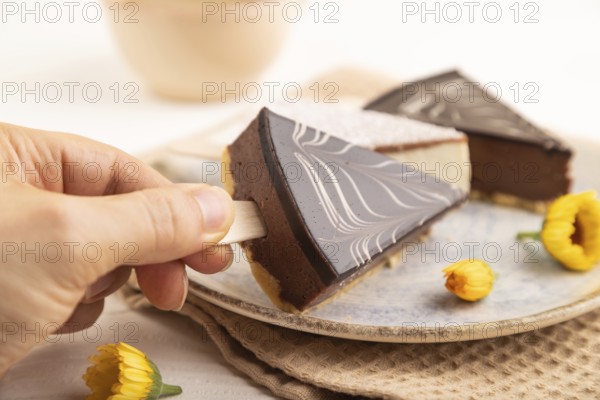 Chocolate and Vanilla Cake pops Marshmallow with hand with cup of coffee on white wooden background and beige linen textile. side view, close up, selective focus hold