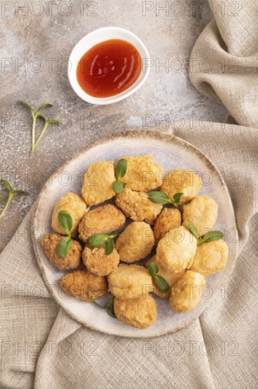 Fried crispy Chicken Nuggets with ketchup, microgreen on brown concrete background and linen textile. top view, flat lay, close up