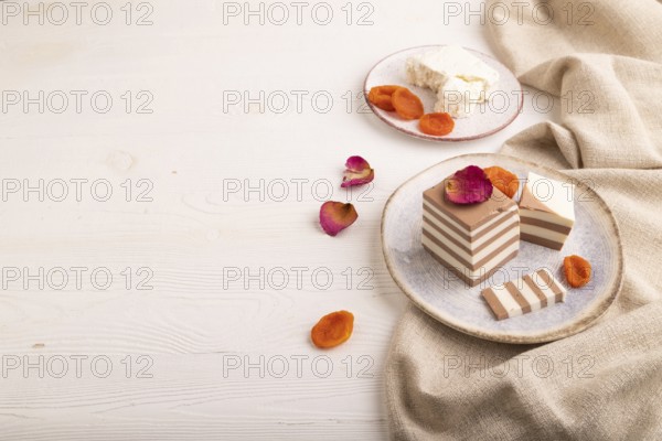 Cocoa and milk jelly with dried apricots on white wooden background and linen textile, side view, copy space, minimalism