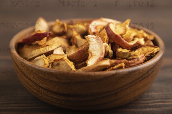 Dried Apples in wooden bowl on brown wooden background. Side view, close up, healthy food, minimalism. sweet, selective focus