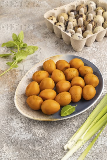 Pile of Smoked Quail eggs on plate on a brown concrete background. side view, close up
