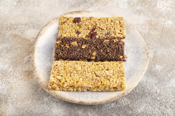 Granola bars with caramel, nuts, flakes in ceramic plate on brown concrete background. Side view, close up