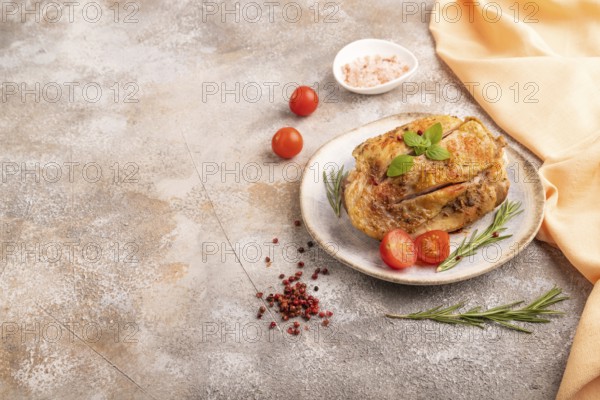 Fried Turkey Thigh with spices and rosemary on plate on brown concrete background and orange linen textile. side view, copy space