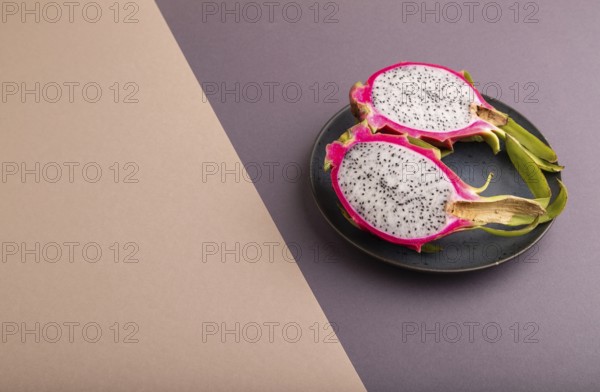 Ripe Pitaya on blue plate on brown and beige pastel paper background, side view, copy space, minimalism