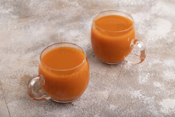 Two glasses with carrot juice, on brown concrete background. Diet, healthy eating concept. side view, close up, minimalism