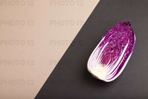 Purple Chinese cabbage on brown and black pastel paper background, side view, copy space, minimalism