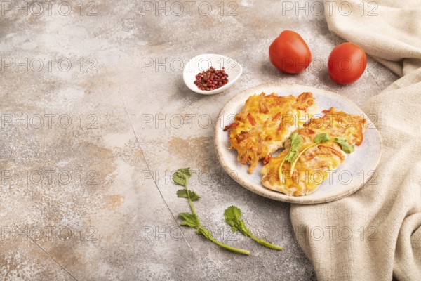 Baked chicken meat with cheese and tomatoes on brown concrete background and linen textile. side view, copy space
