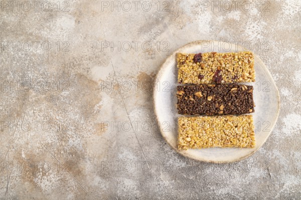 Granola bars with caramel, nuts, flakes in ceramic plate on brown concrete background. Top view, flat lay, copy space