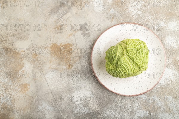 Green lettuce on plate on brown concrete background. Top view, copy space, flat lay. healthy food, vegetable, minimalism