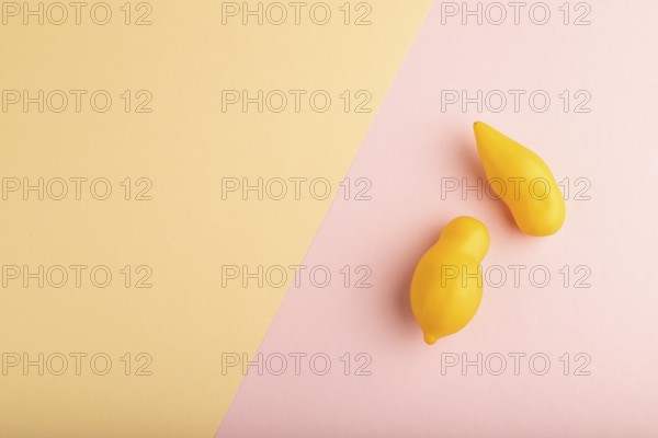 Yellow tomatoes on pink and orange pastel paper background. Top view, copy space, flat lay. healthy food, vegetable, minimalism