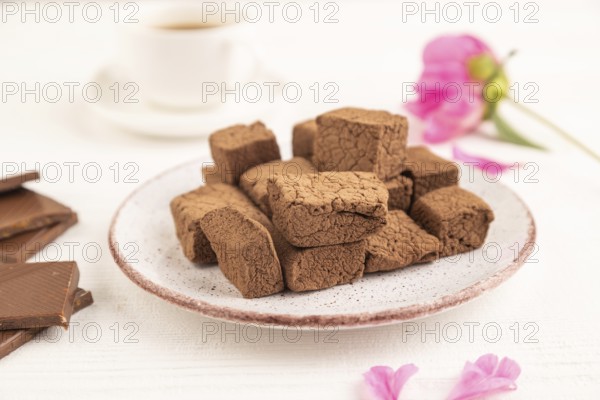 Chocolate marshmallow with cup of coffee on white wooden background. side view, close up, selective focus