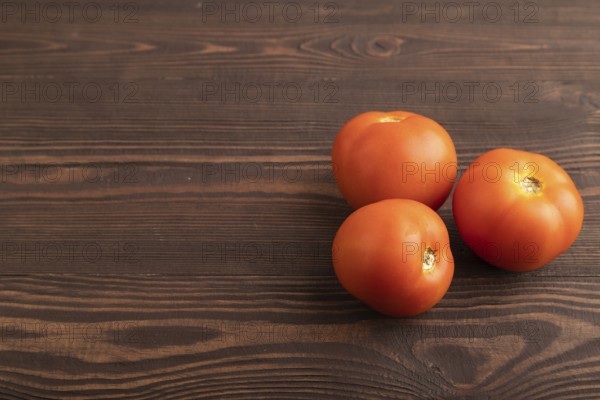 Red tomato on brown wooden background. Side view, copy space. healthy food, vegetable, minimalism