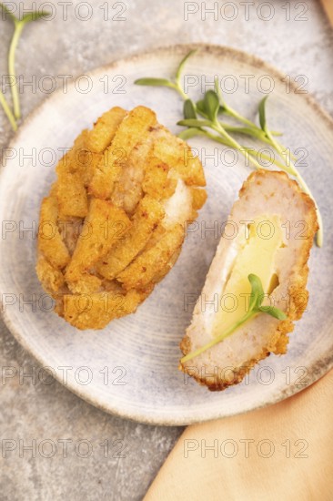 Chicken Schnitzel on blue plate with microgreen on brown concrete background and orange linen textile. side view, close up, selective focus