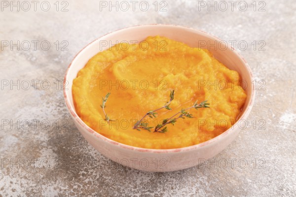 Sweet potato porridge in ceramic bowl on brown concrete background. Diet, healthy eating concept. side view, copy space