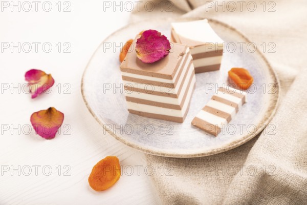 Cocoa and milk jelly with dried apricots on white wooden background and linen textile, side view, close up, minimalism, selective focus