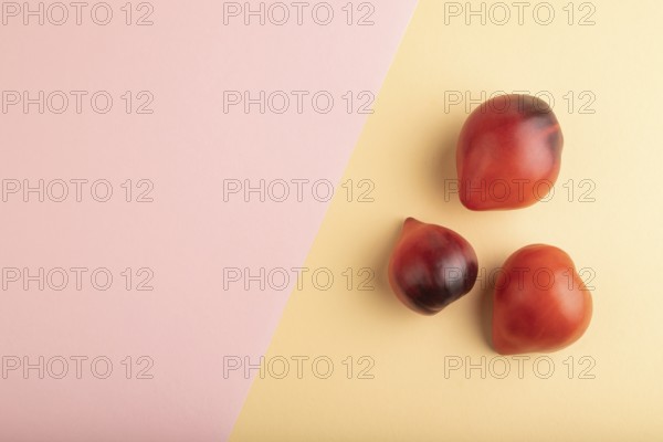 Red Heart shape tomatoes on pink and orange pastel paper background. Top view, copy space, flat lay. healthy food, vegetable, minimalism
