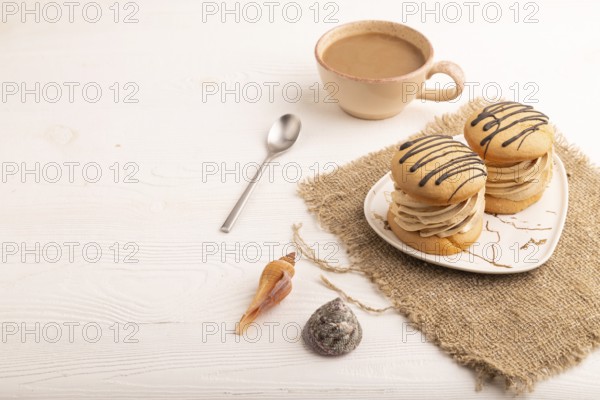 Caramel Cream Cakes on white wooden background and linen textile, cup of coffee, side view, copy space