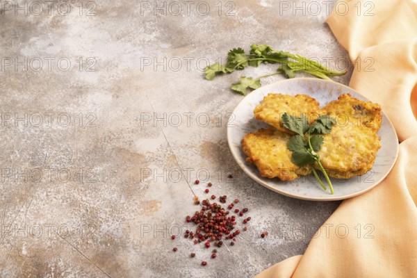 Fried crispy Chicken pancakes on brown concrete background and orange linen textile. side view, copy space